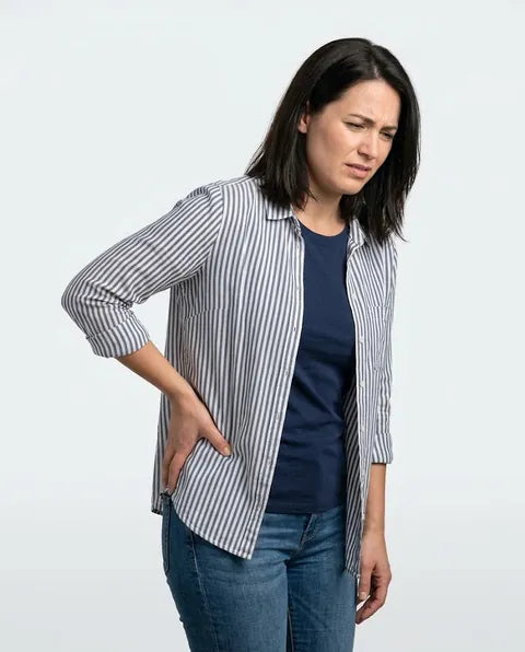 A woman wincing, her hand pressed on her hip