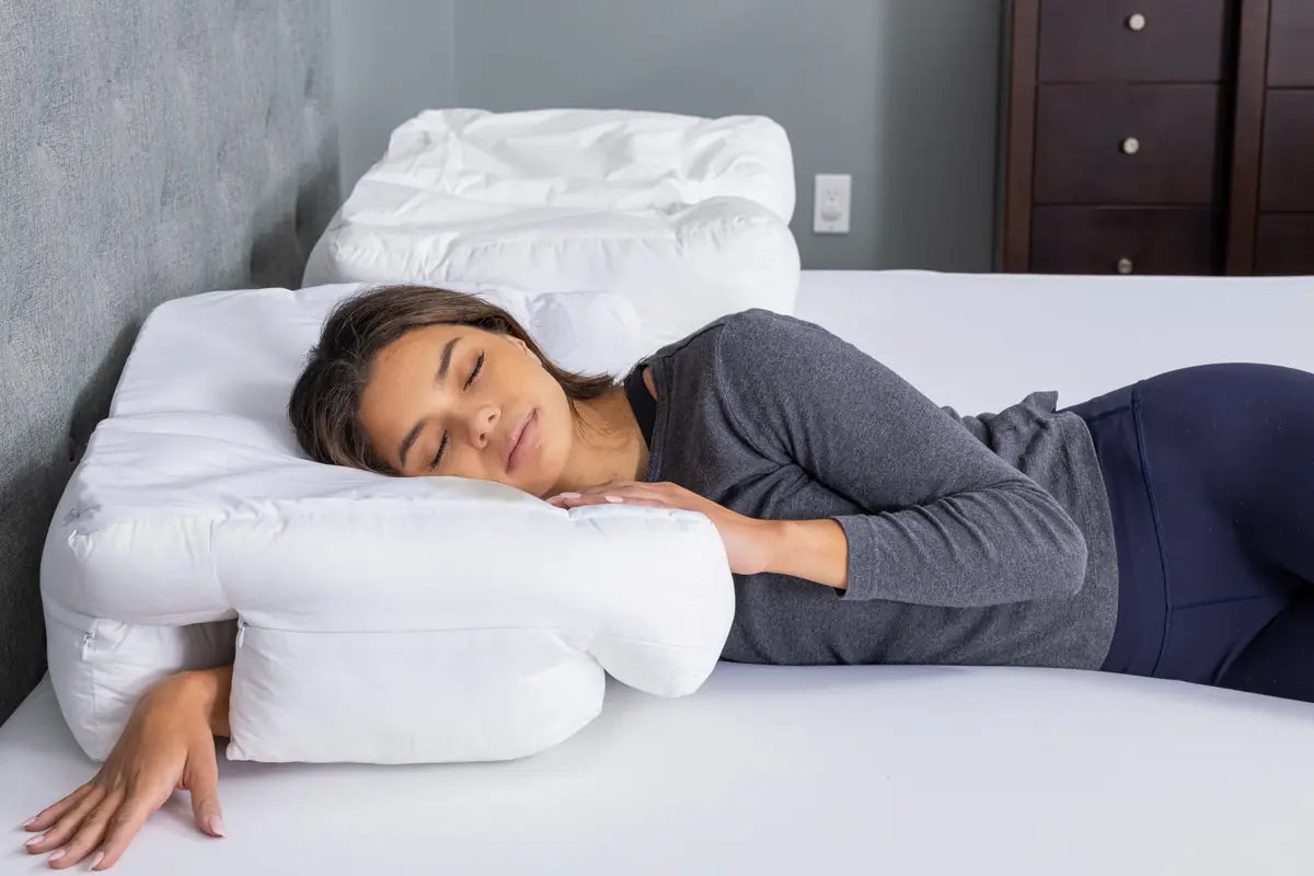 Wife Pillow 2.0 in a bedroom, a woman asleep on her side with her arm through the arm tunnel